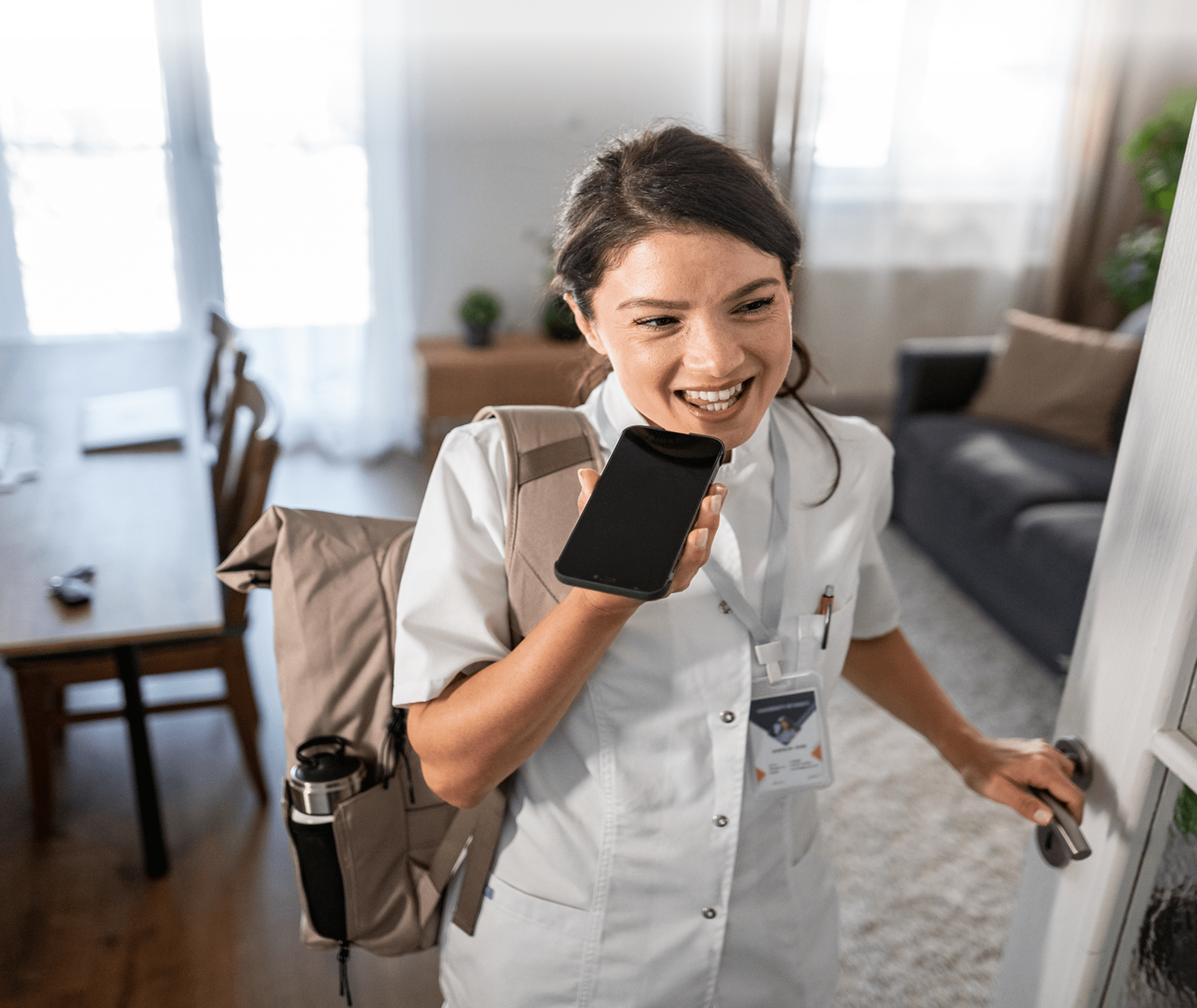 Smiling nurse talking on a phone with a walker beside her.